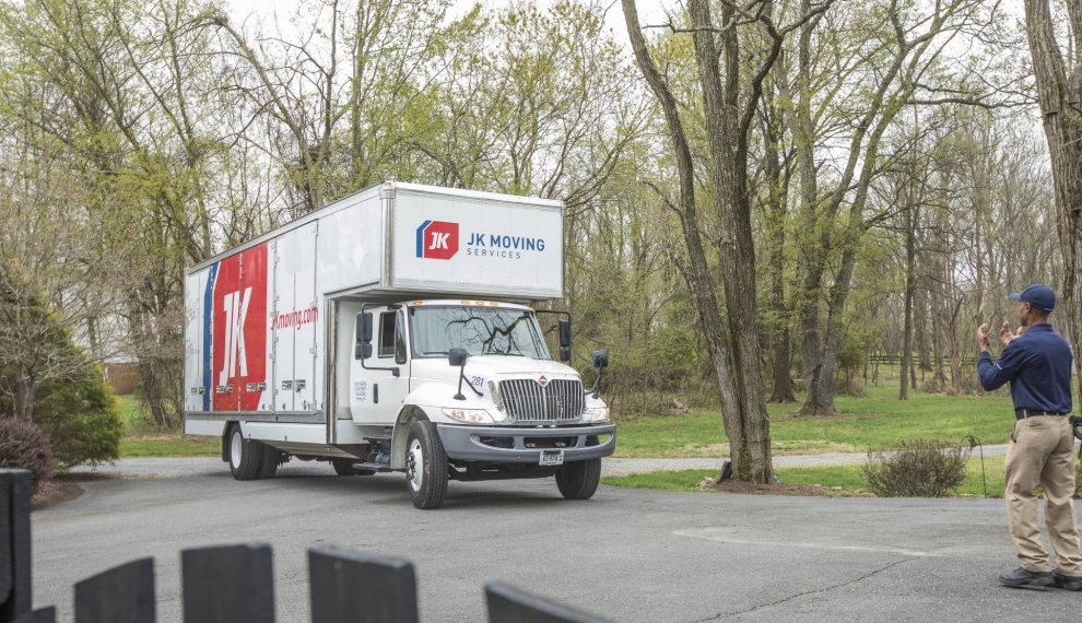 A JK Moving professional directing a truck