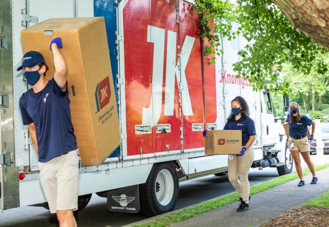 JK Moving professionals carrying boxes to truck in ppe