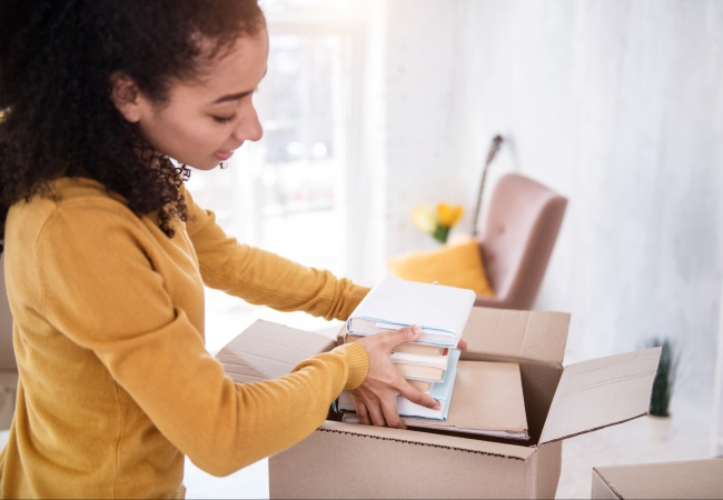 College girl packing books in moving box