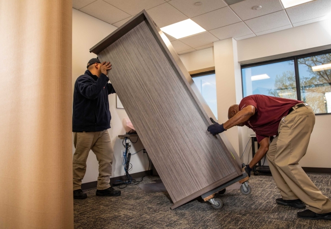 Two men picking up a desk during an office furniture decommissioning process