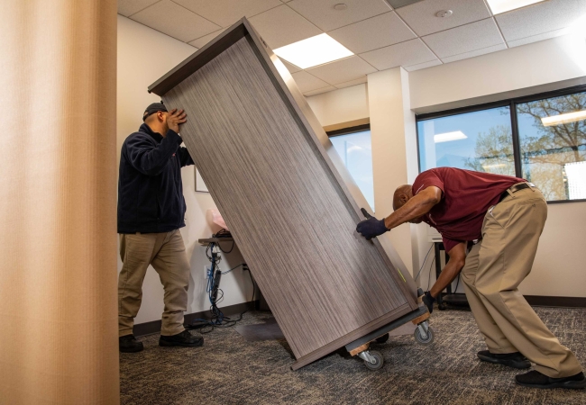 Two men picking up a desk during an office furniture decommissioning process