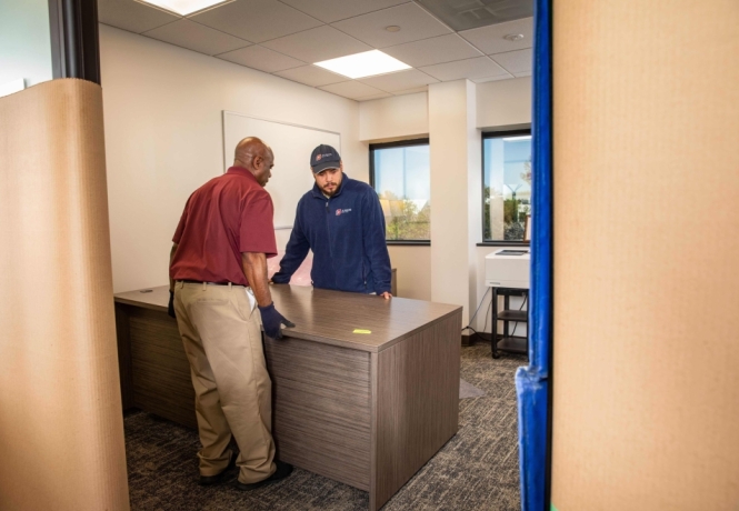 Two men moving a desk during an office decommissioning assignment