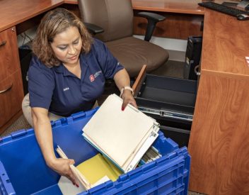 office moving tips, JK Moving team member packing office supplies in moving box