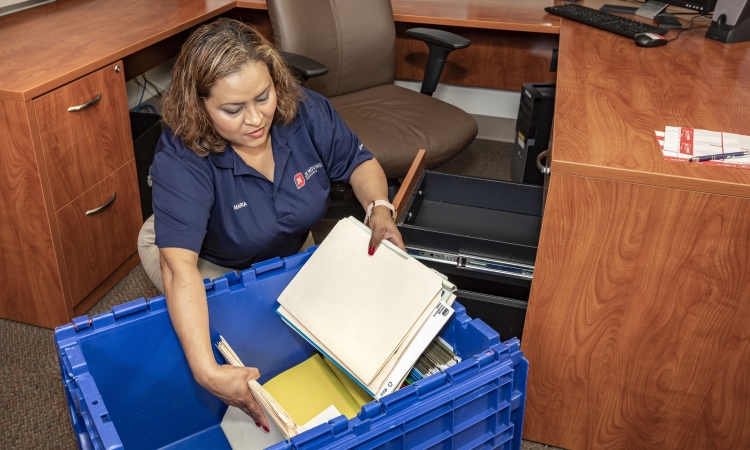 office moving tips, JK Moving team member packing office supplies in moving box