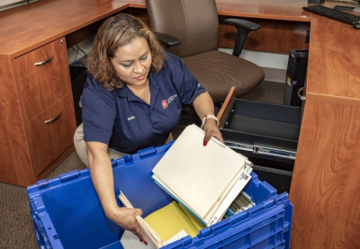 office moving tips, JK Moving team member packing office supplies in moving box