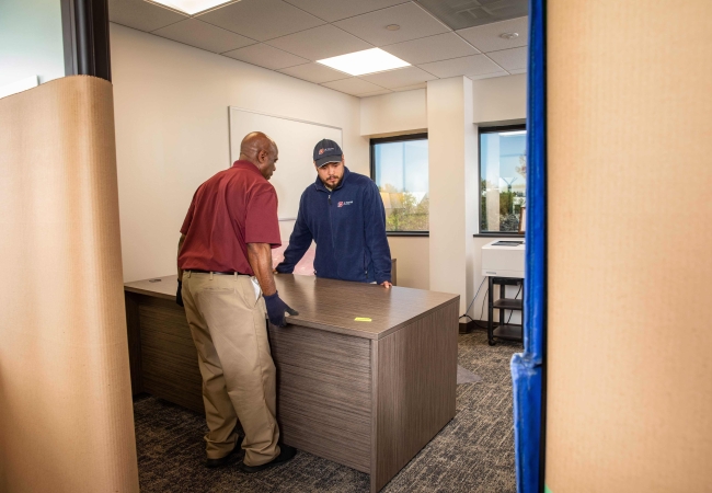 Two men moving a desk during an office decommissioning assignment
