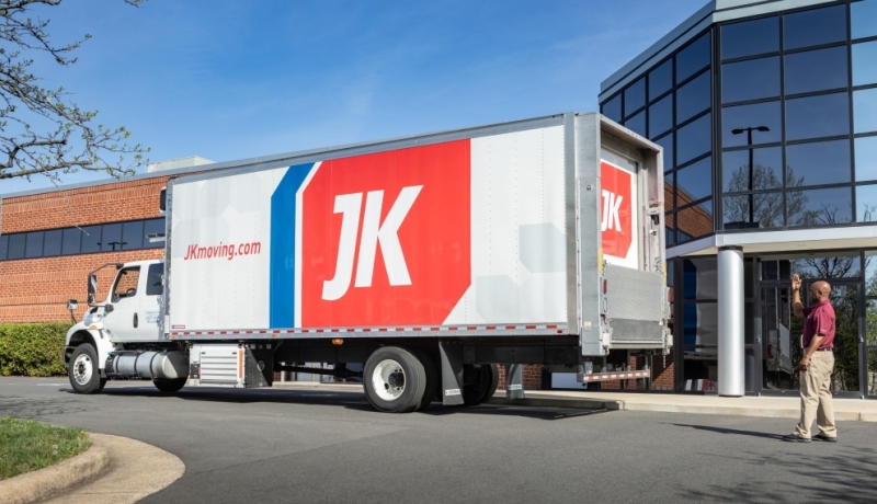 A JK Moving Services truck parked outside a commercial office building, ready for secure IT equipment relocation, highlighting professional transport and local expertise in business-critical moves.
