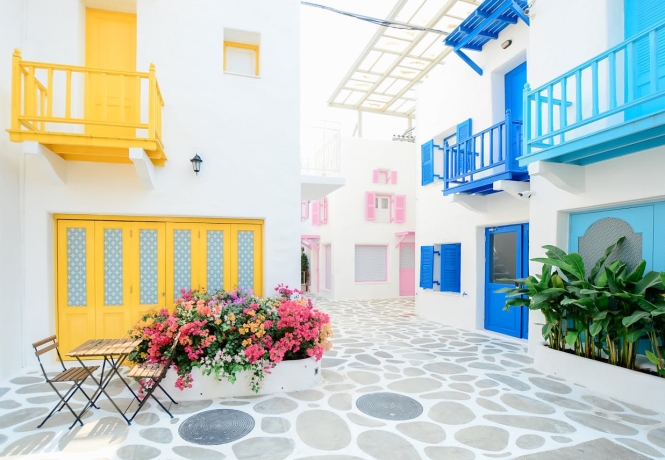 Colorful Greek street with blue and yellow doors and flowers, representing the charm and lifestyle of relocating to Greece