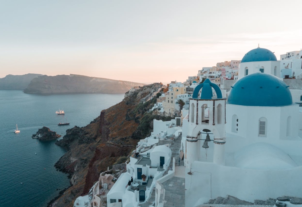 Scenic view of Santorini’s whitewashed houses and blue domes at sunset, symbolizing a peaceful new life after moving to Greece from the USA