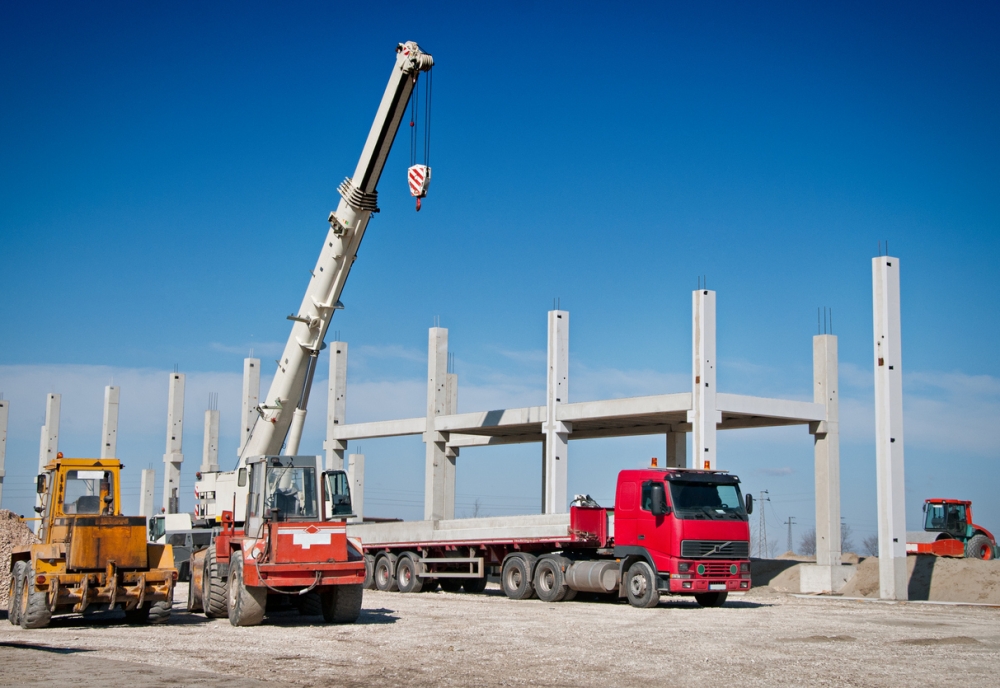 Mobile crane lifting structural steel at an industrial construction site for heavy equipment placemen