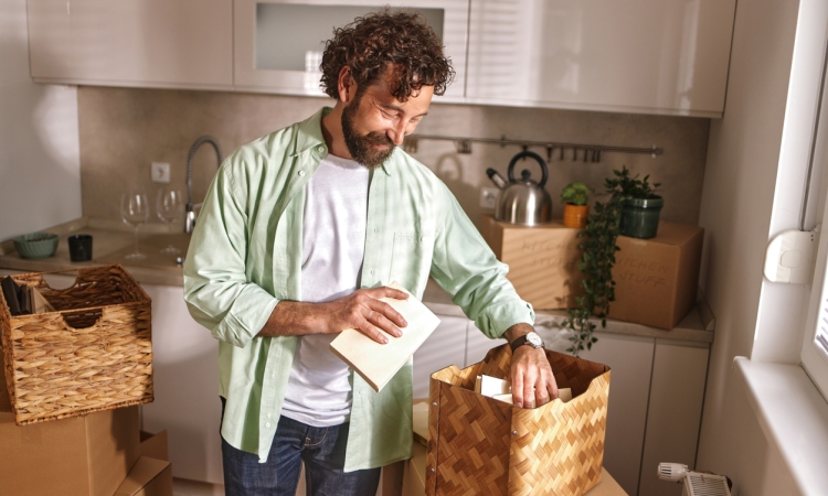 Person packing belongings into moving boxes in a new home while preparing for a solo move