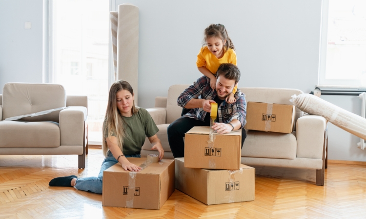 Family packing moving boxes in a living room while preparing for a room-by-room move