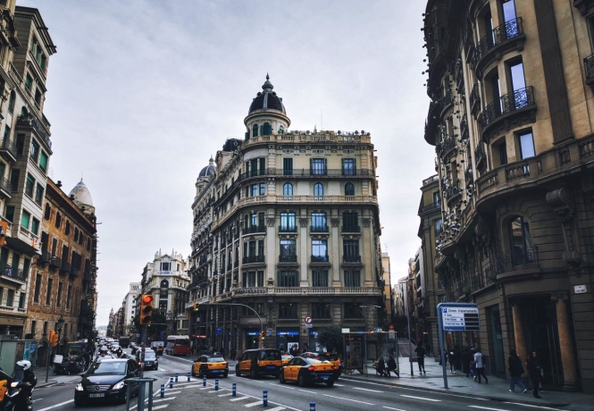 A busy Barcelona avenue lined with classic Eixample architecture and taxis