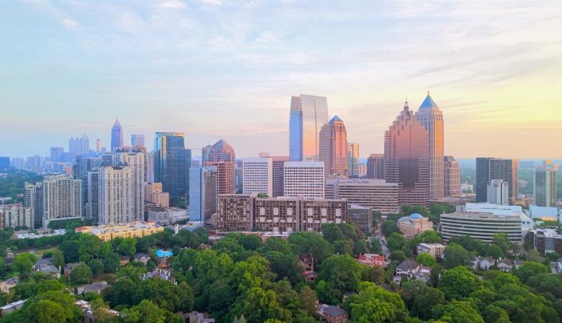 Atlanta skyline rising above tree-lined neighborhoods at sunset