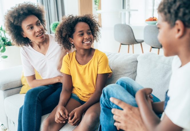 Mother and two children relaxing and talking on the couch in their newly settled home