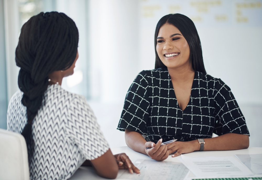 Smiling woman meets with a JK specialty services advisor at a desk to plan relocation services